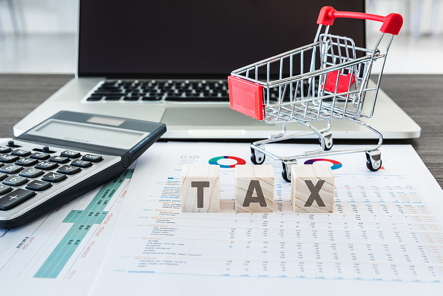 Business E-Commerce Online and Financial Tax Accounting Concept., Calculator and Mini Cart on Data Fact Sheet in Front of Personal Computer Laptop Background., Customer shopping and E-Payment Concept.