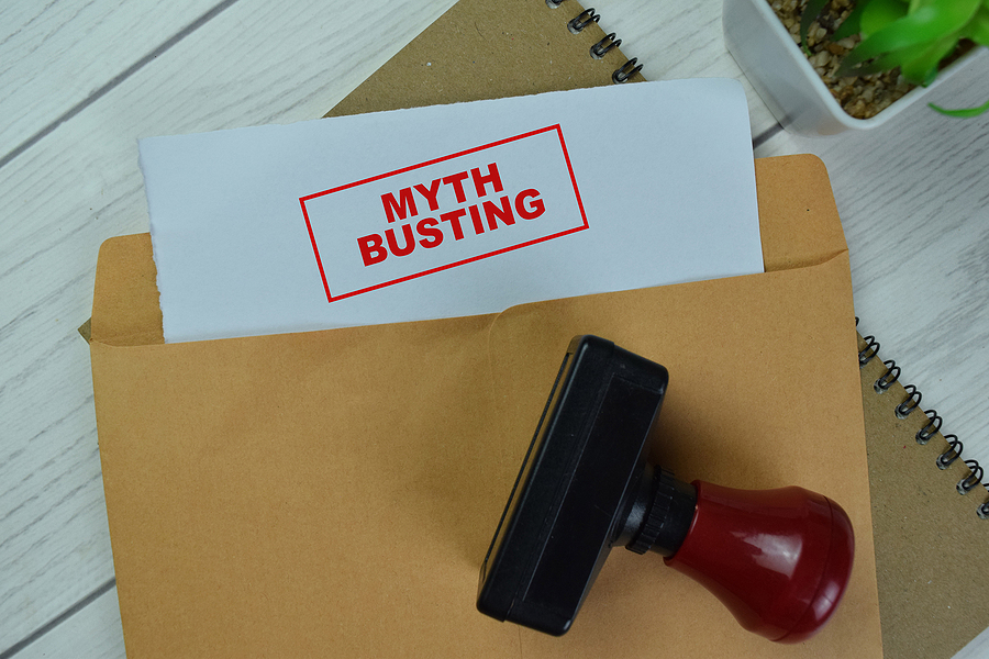 Concept of Red Handle Rubber Stamper and Myth Busting text above Brown envelope isolated on on Wooden Table.