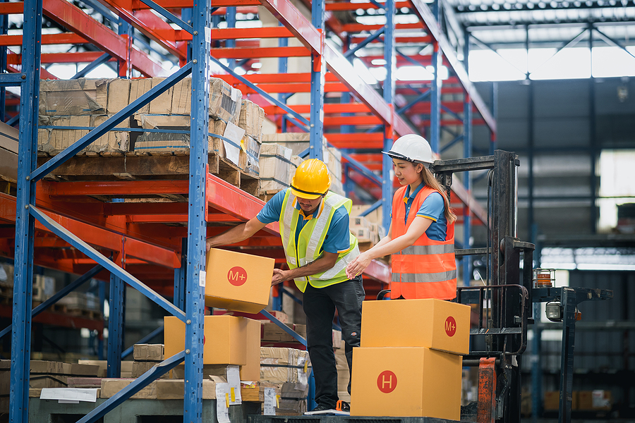 warehouse workers lifting box of goods to place on the shelf and standing on forklift in warehouse factory store, worker counting check stock. inventory count